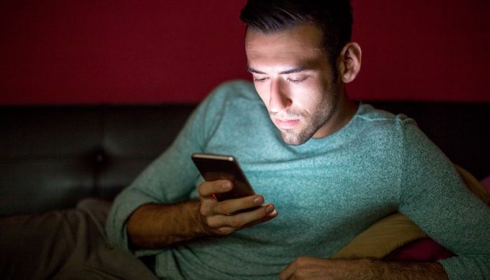 serious-man-using-smartphone-sofa-night-1.jpg